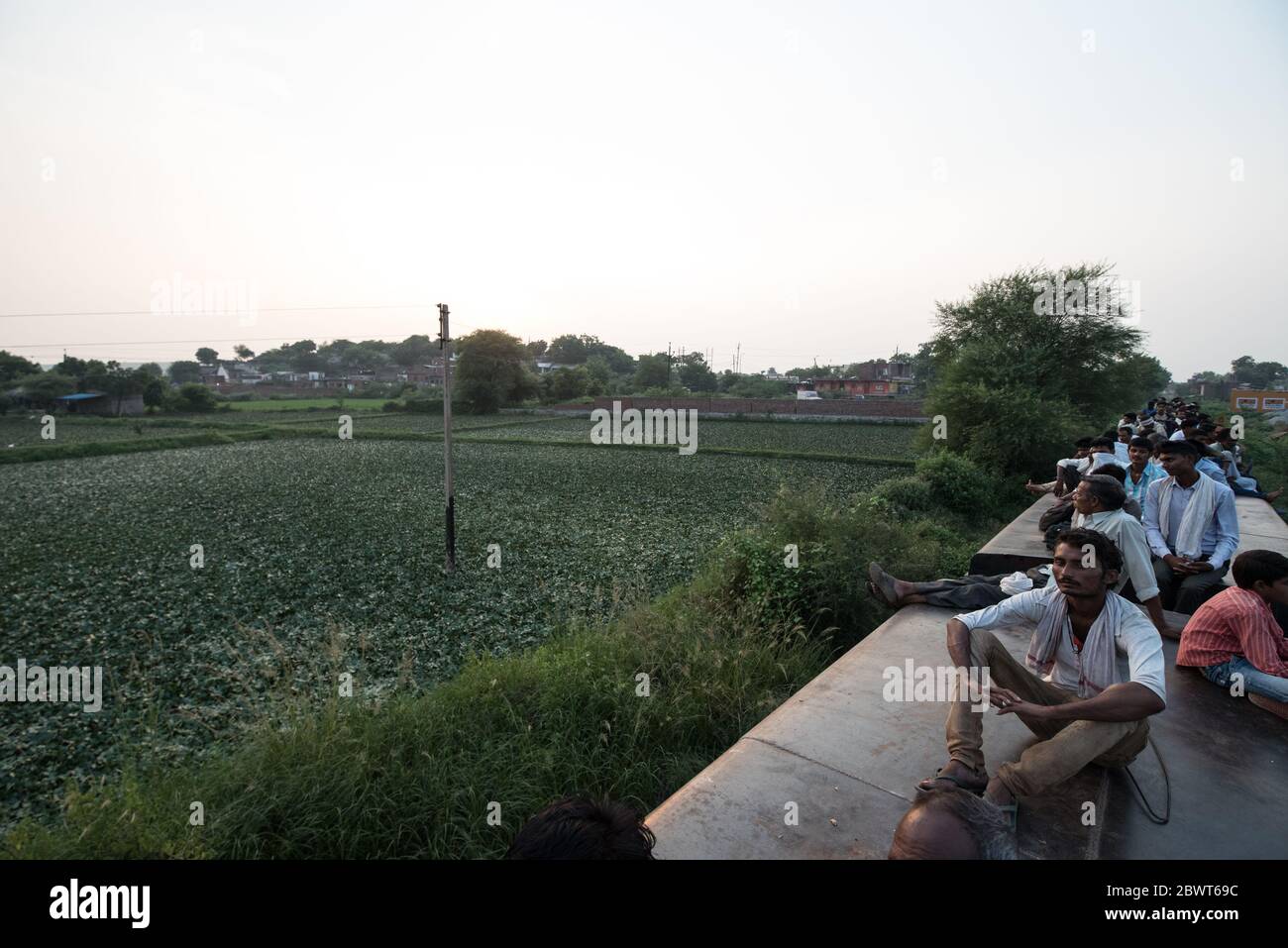 Des hommes au sommet d'un train surpeuplé traversant la campagne dans le Madhya Pradesh, en Inde. Chemins de fer indiens. Banque D'Images