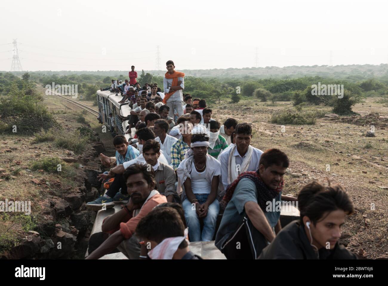 Des hommes au sommet d'un train surpeuplé traversant la campagne dans le Madhya Pradesh, en Inde. Chemins de fer indiens. Banque D'Images