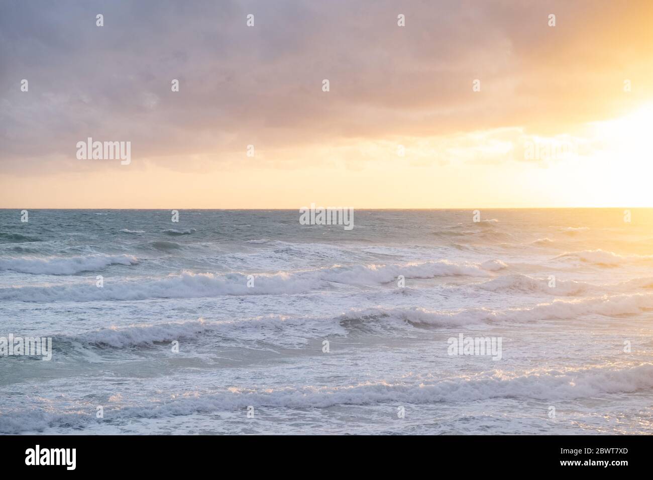 Mer de Stormy Jonio, Italie du Sud, mousse créée par le mouvement des vagues à l'heure du coucher du soleil, un jour avec le ciel plein de nuages. Banque D'Images