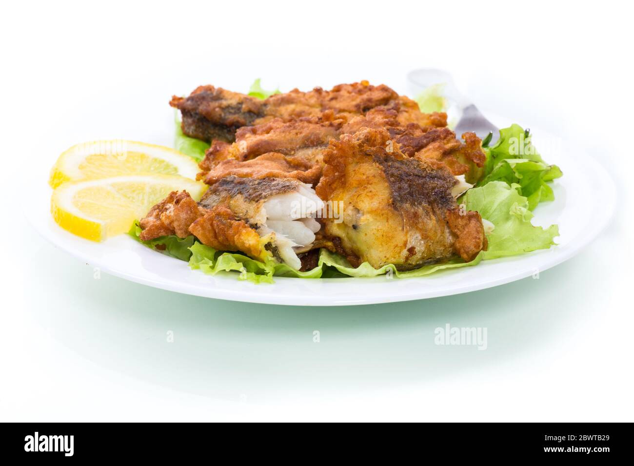 poisson frit au merlu dans une pâte avec laitue et citron dans une assiette Banque D'Images