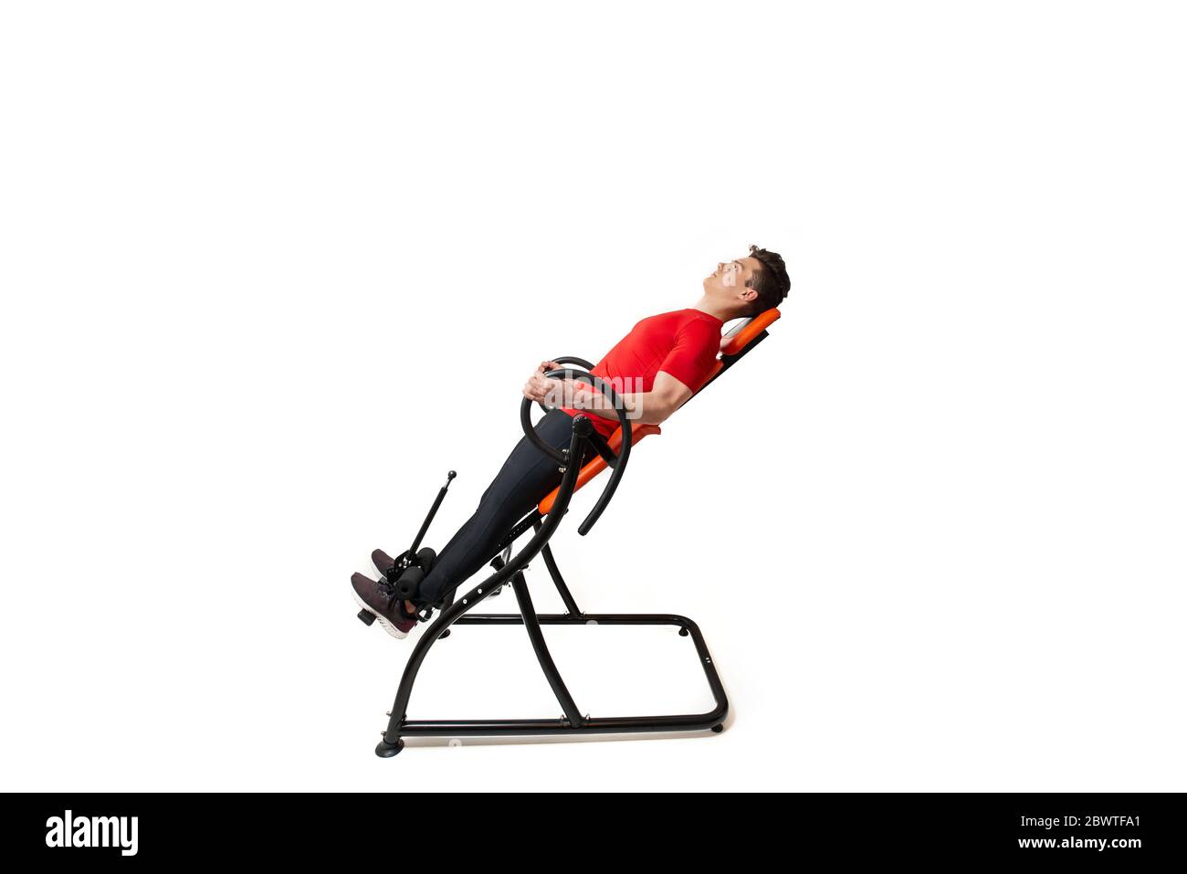 Homme faisant de l'exercice sur la table d'inversion pour sa douleur dorsale, isolé sur blanc Banque D'Images
