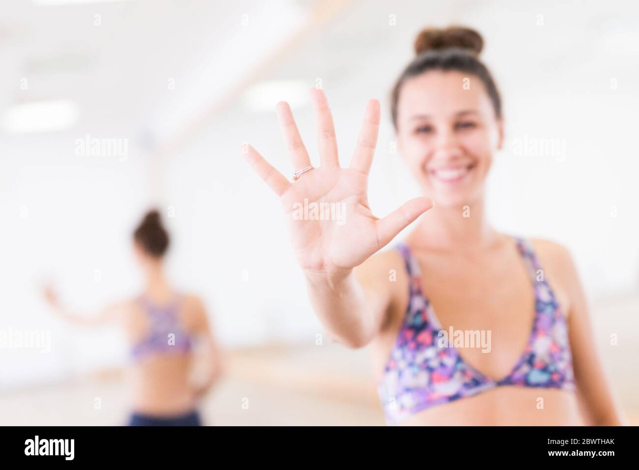 Portez un vêtement sportif sportif qui vous fera sourire en montrant la paume ouverte de votre caméra dans un studio de yoga. Style de vie urbain actif. Banque D'Images