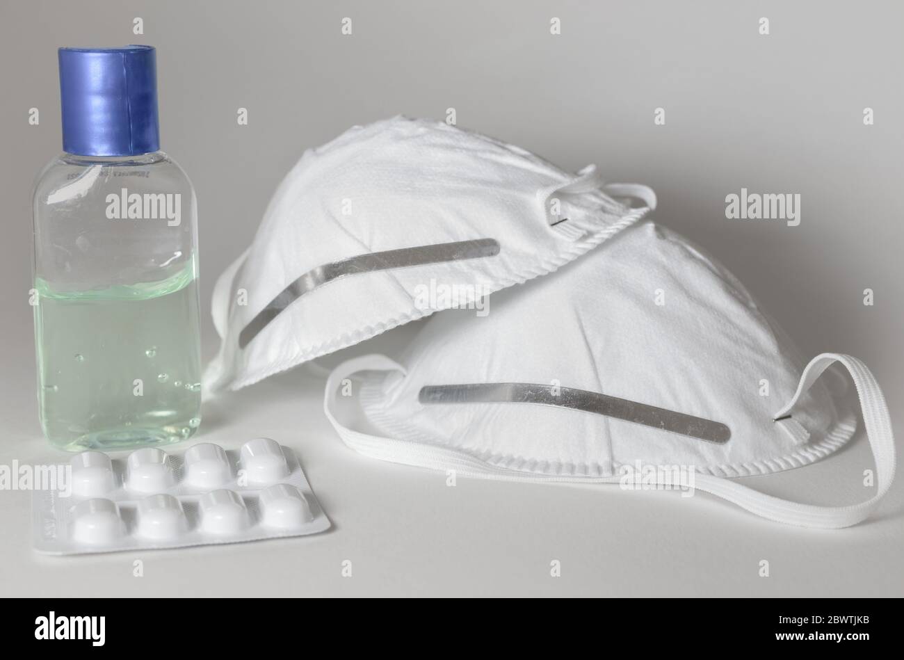 Désinfectant pour les mains, médicaments et deux masques isolés sur fond blanc Banque D'Images