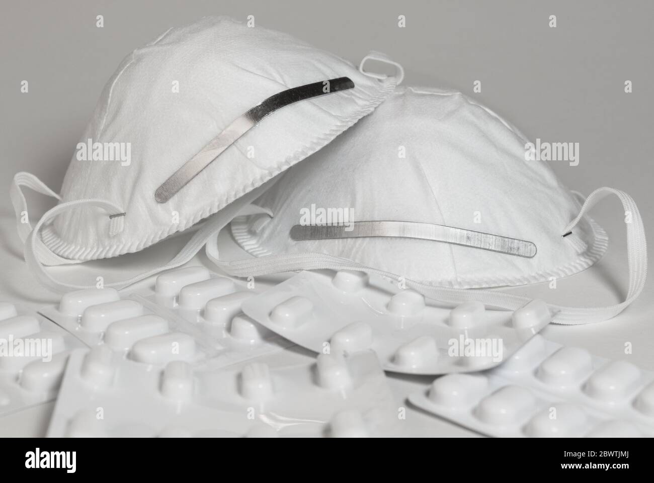 Deux masques faciaux et une pile de paquets de médicaments isolés sur fond blanc Banque D'Images