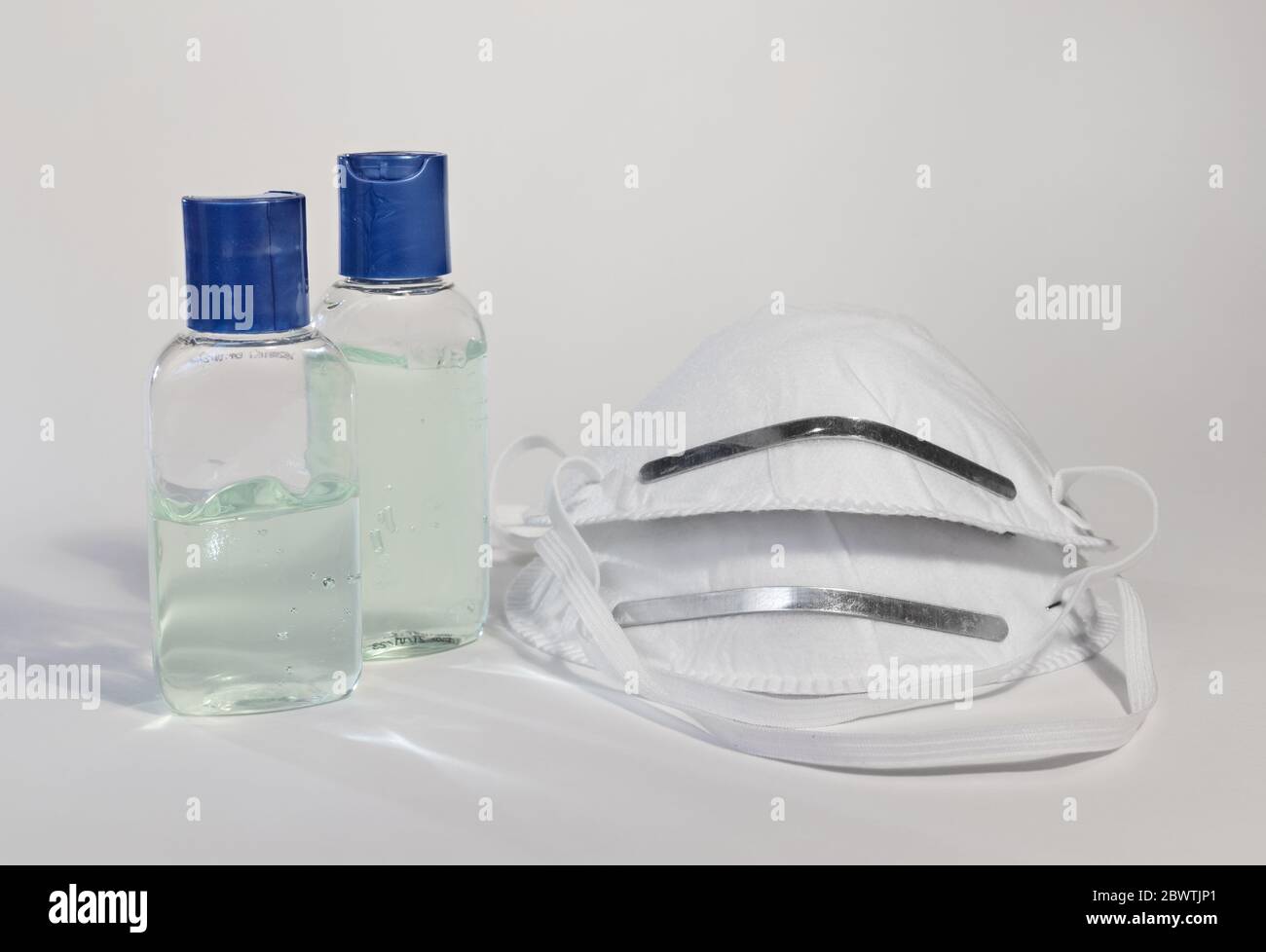 Deux bouteilles de désinfectant pour les mains et masques isolés sur fond blanc Banque D'Images