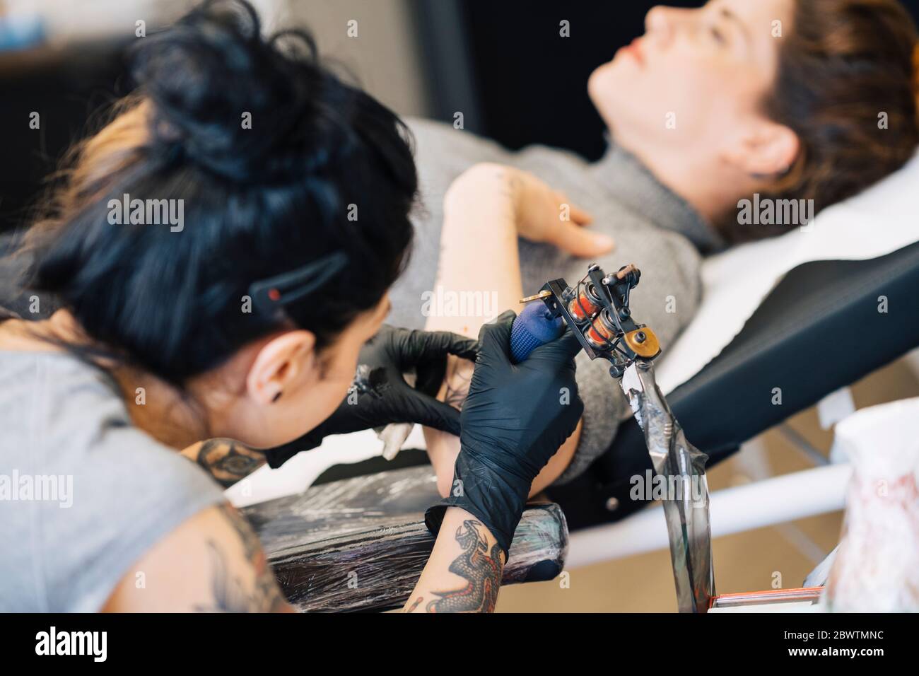 Tatoueur de femme tatouant sur le bras d'une femme Banque D'Images