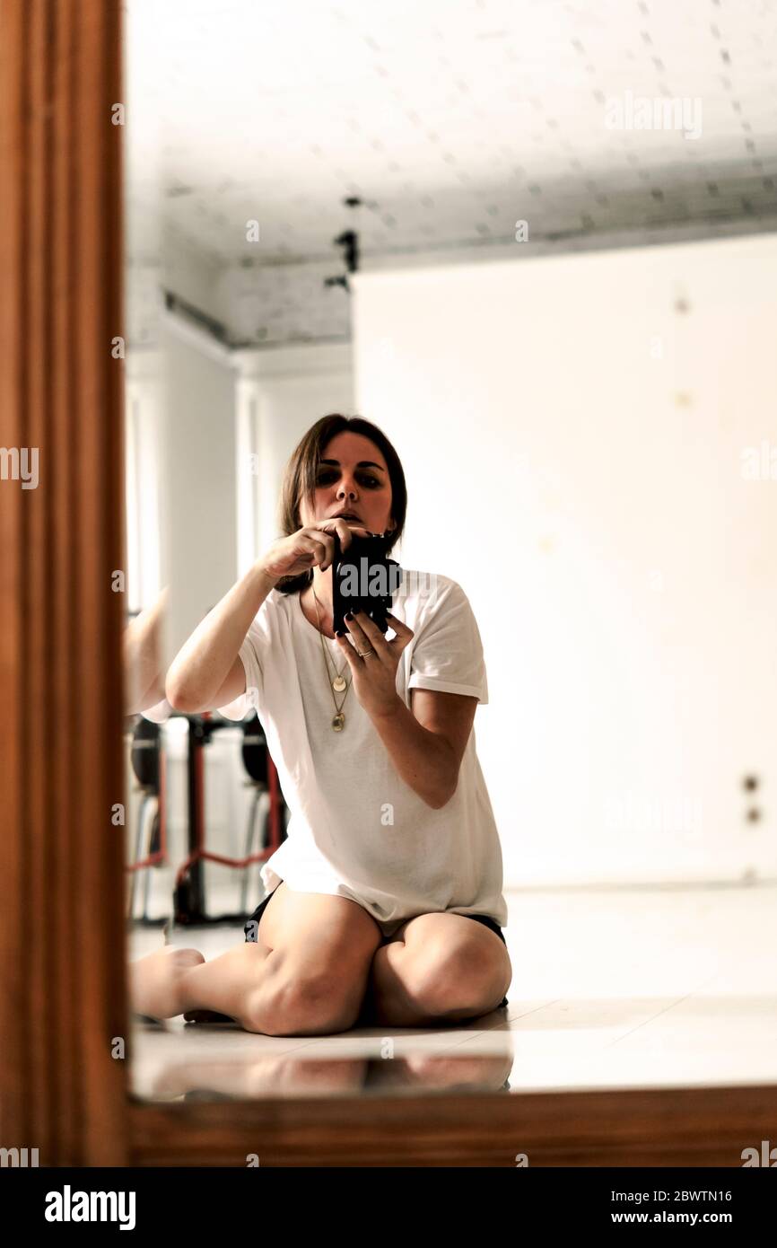 Image miroir d'une femme mûre assise sur le sol prenant des photos avec l'appareil photo Banque D'Images