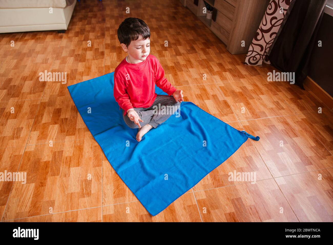 Petit garçon faisant du yoga à la maison Banque D'Images