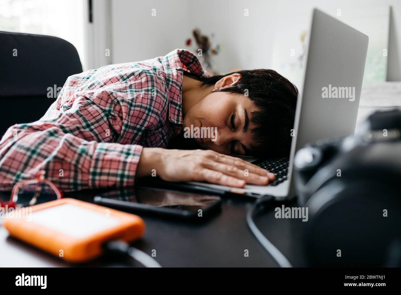 Femme surtraitée dormant sur un ordinateur portable dans le bureau à domicile Banque D'Images