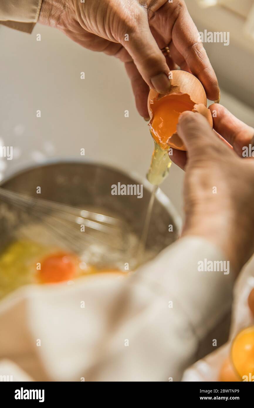 Mains de la femme craquant l'œuf dans le bol Banque D'Images