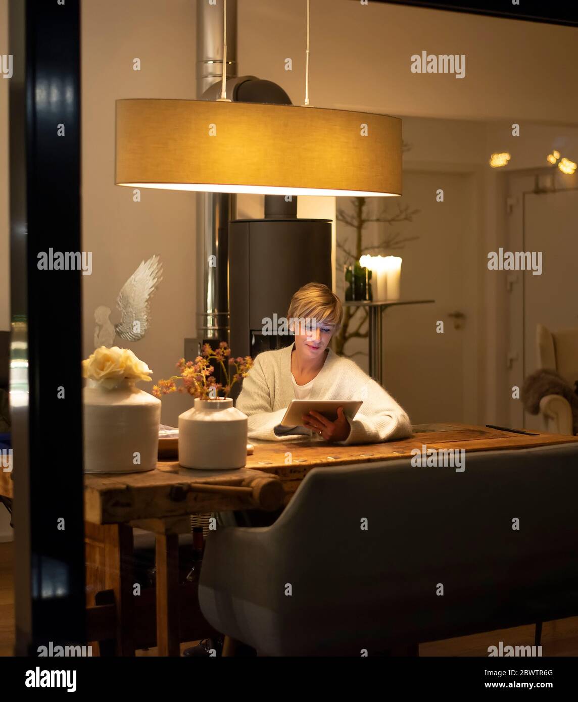 Femme travaillant à la maison avec une tablette numérique tout en étant assise à une table dans le salon Banque D'Images