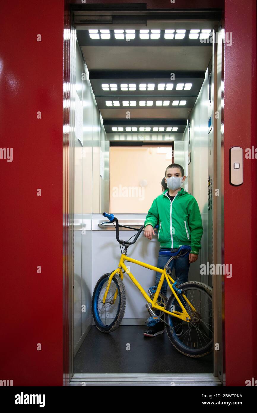 Portrait complet d'un garçon avec vélo debout dans l'ascenseur Banque D'Images
