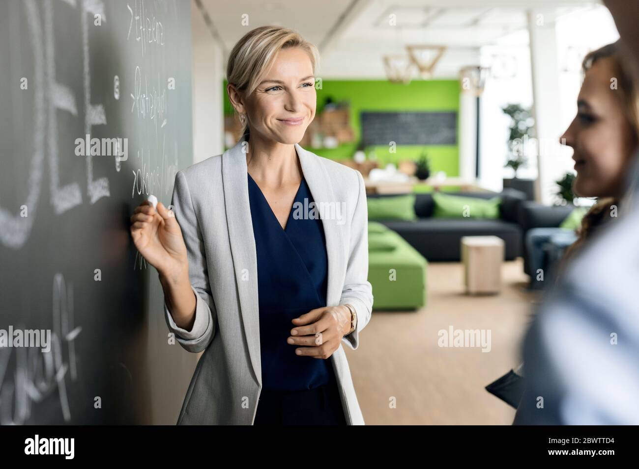 Une femme d'affaires remue-méninges au tableau noir au bureau Banque D'Images