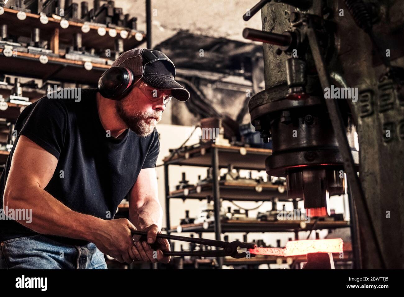 Le fabricant de couteaux travaille avec de l'acier damassé au marteau coulissant hydraulique Banque D'Images