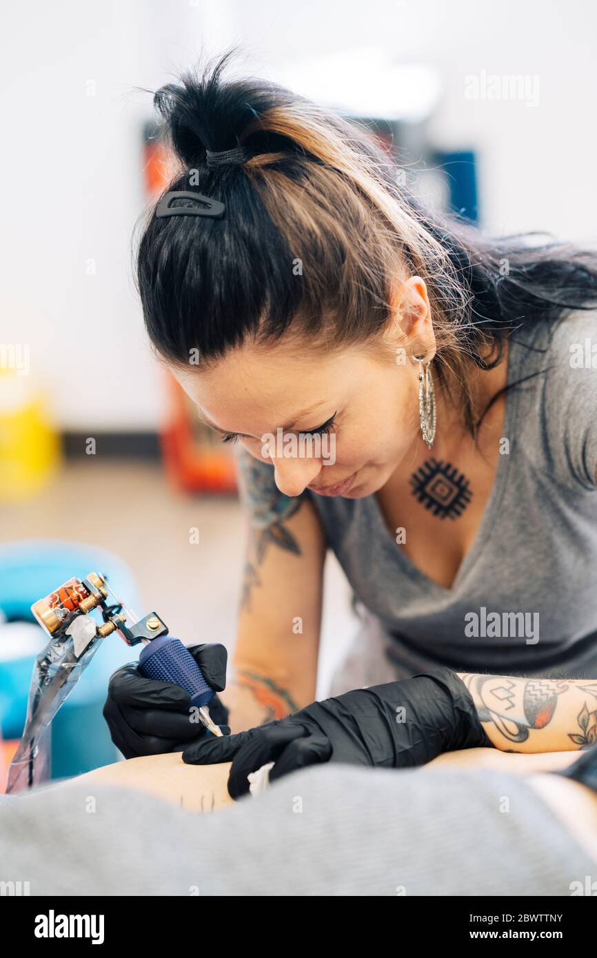 Tatoueur de femme tatouant sur le bras d'une femme Banque D'Images