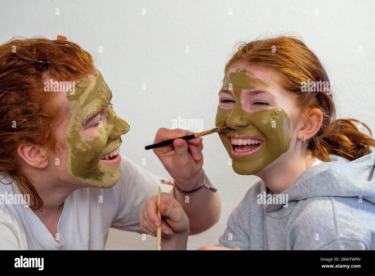 Frère appliquant un masque facial sur le visage de sa sœur Banque D'Images