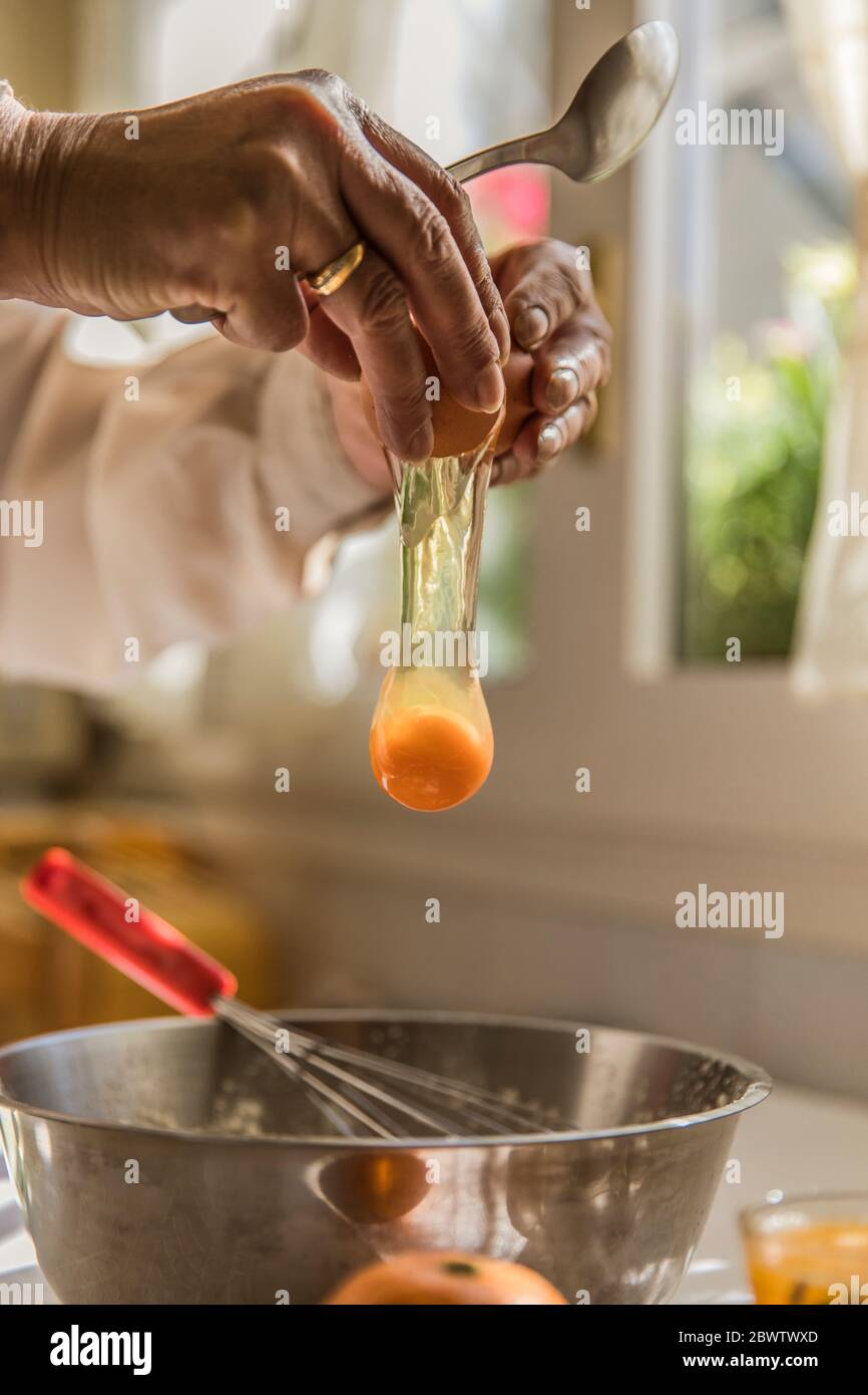 Mains de la femme craquant l'œuf dans le bol Banque D'Images