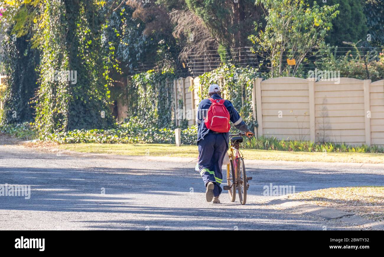 Alberton, Afrique du Sud - cycliste mâle non identifié poussant son vélo avec des achats et une image de sac à dos en format horizontal Banque D'Images