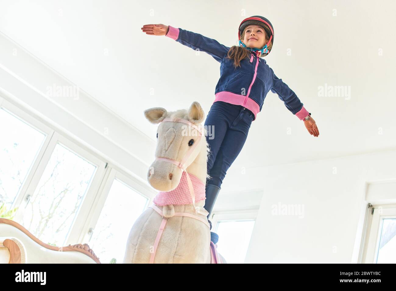 Fille debout sur le cheval de jeu à la maison Banque D'Images