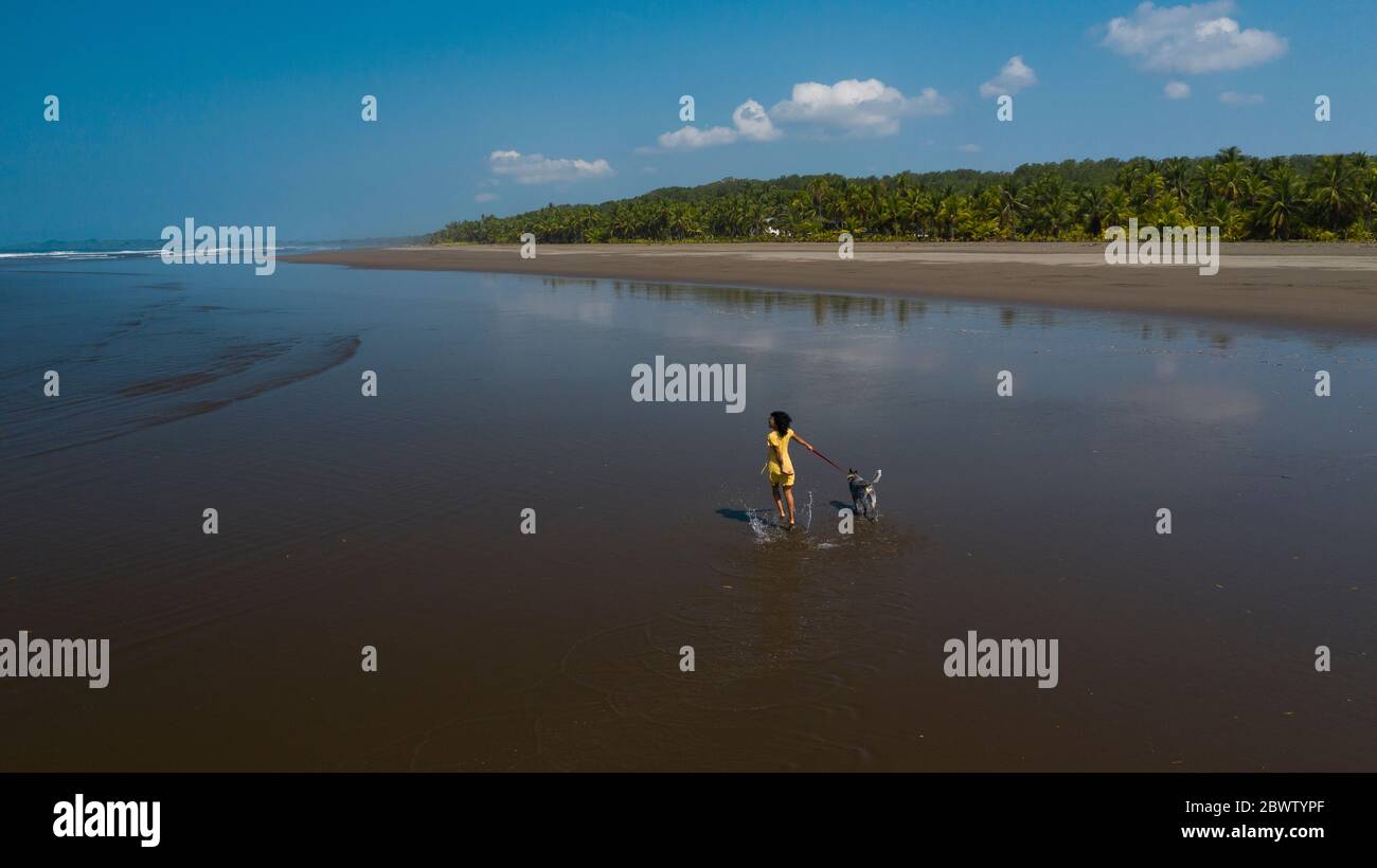Une jeune femme insouciante prend son chien pour une promenade à la plage, Costa Rica Banque D'Images