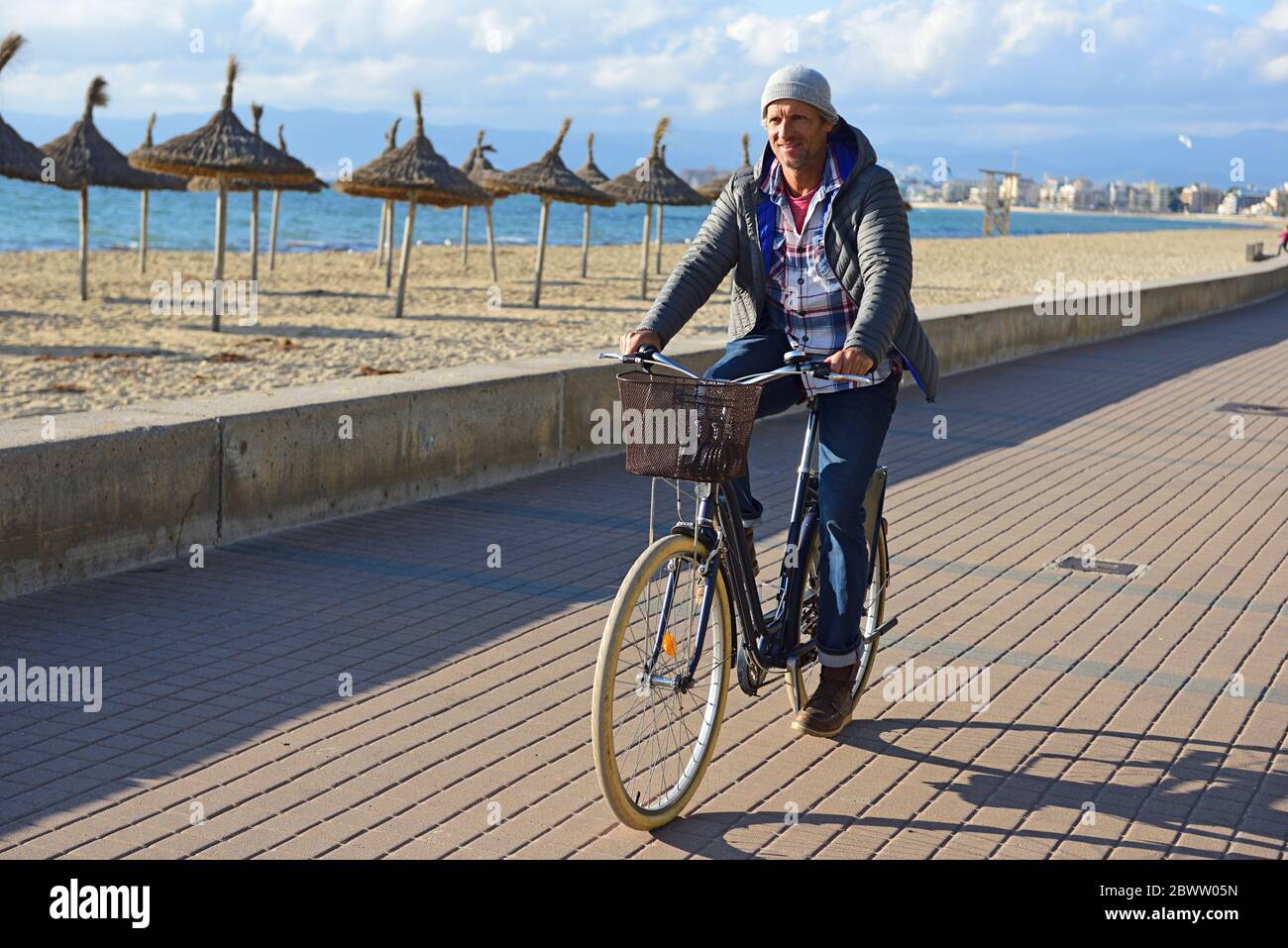 Homme à vélo sur la promenade de la plage en hiver Banque D'Images