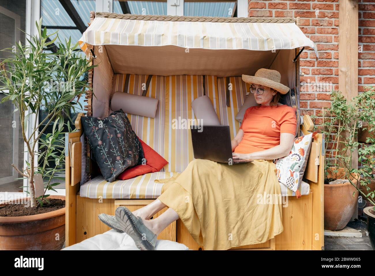 Femme d'âge mûr assise sur la terrasse travaillant sur un ordinateur portable Banque D'Images