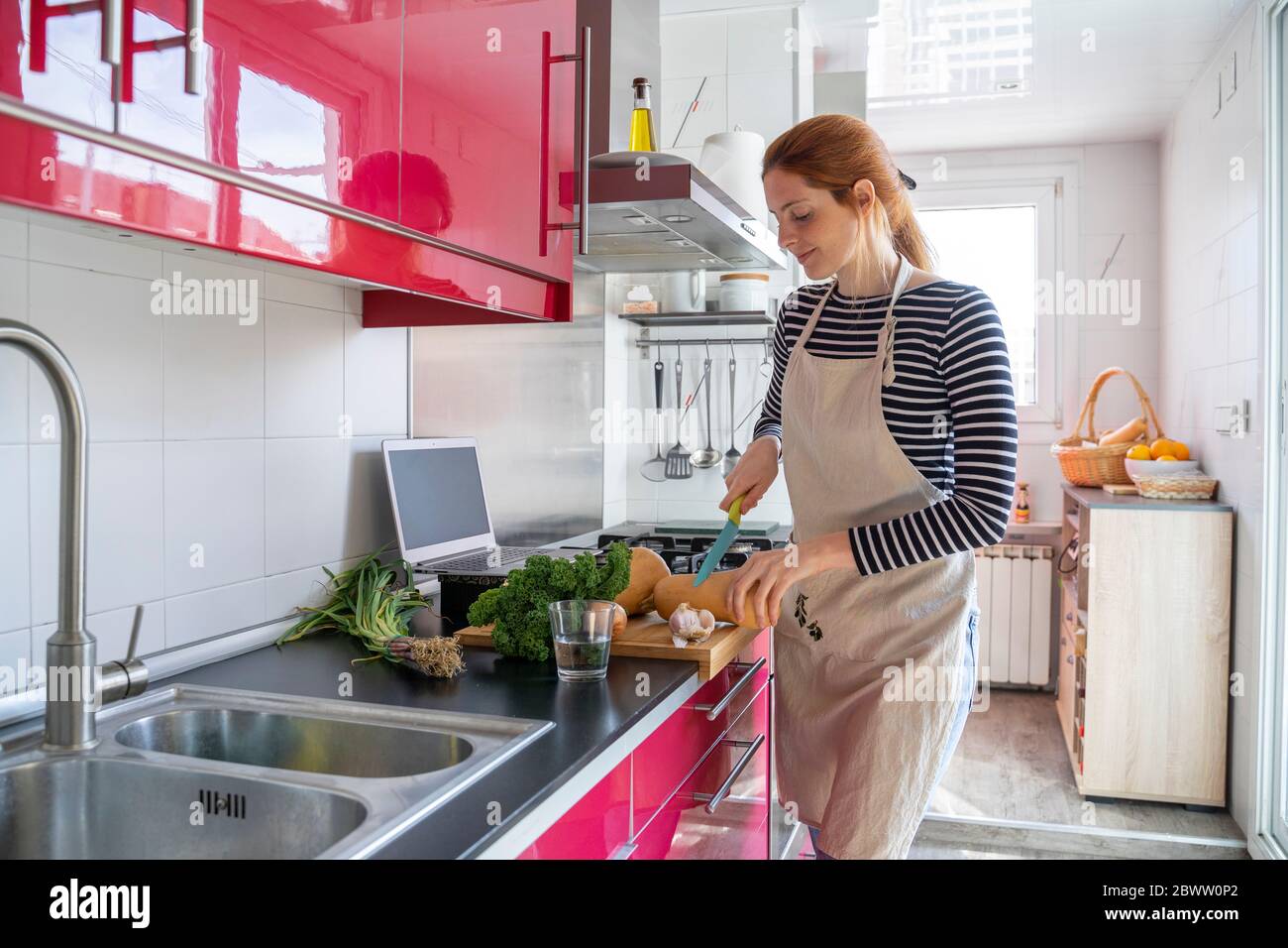 Jeune femme préparant un repas sain, en utilisant des recettes en ligne Banque D'Images