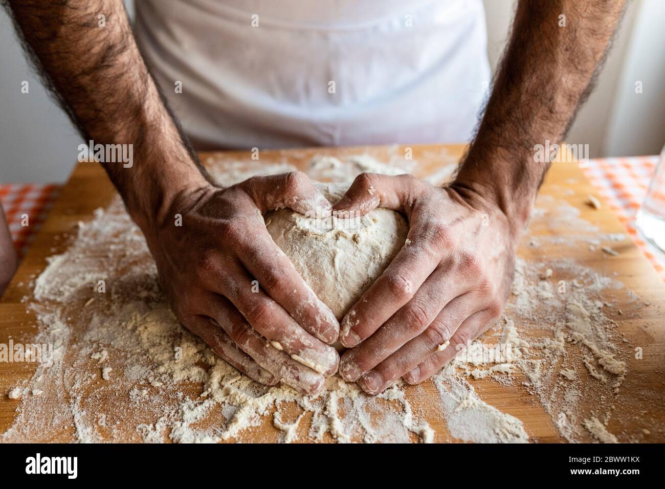 Les mains de l'homme façonnent le cœur sur la boule de pâte Banque D'Images