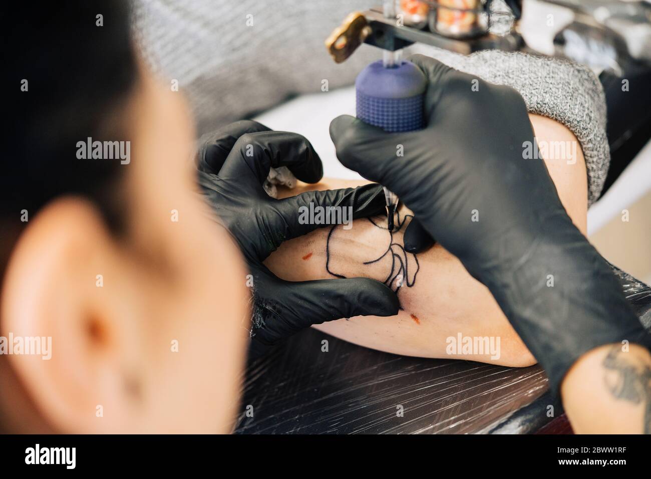 Tatoueur de femme tatouant sur le bras d'une femme Banque D'Images