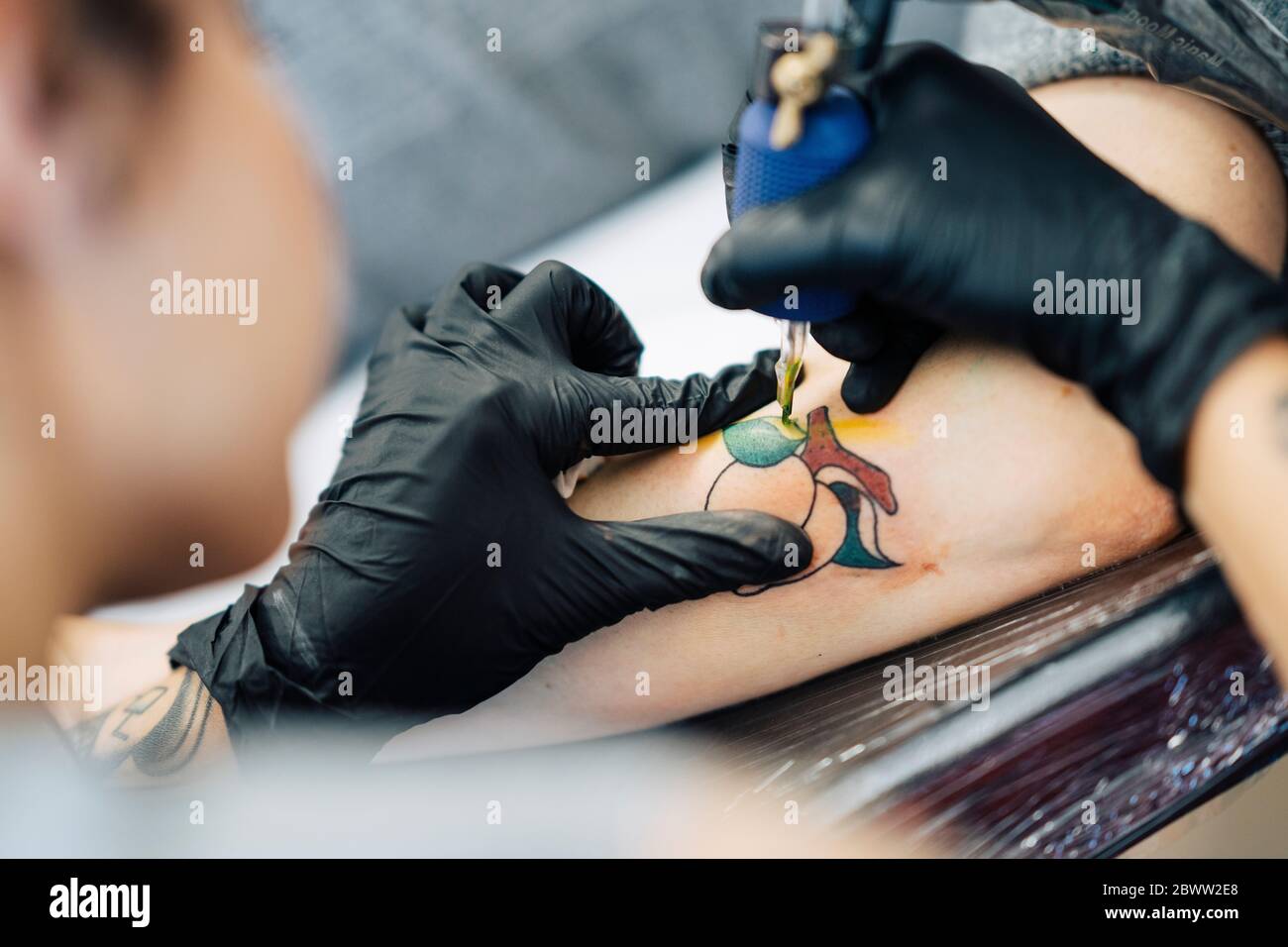 Tatoueur de femme tatouant sur le bras d'une femme Banque D'Images