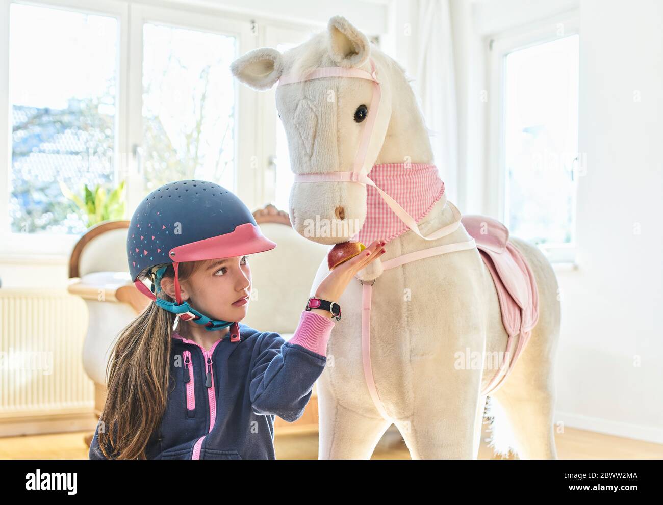 Fille nourrissant son cheval jouet à la maison Photo Stock - Alamy