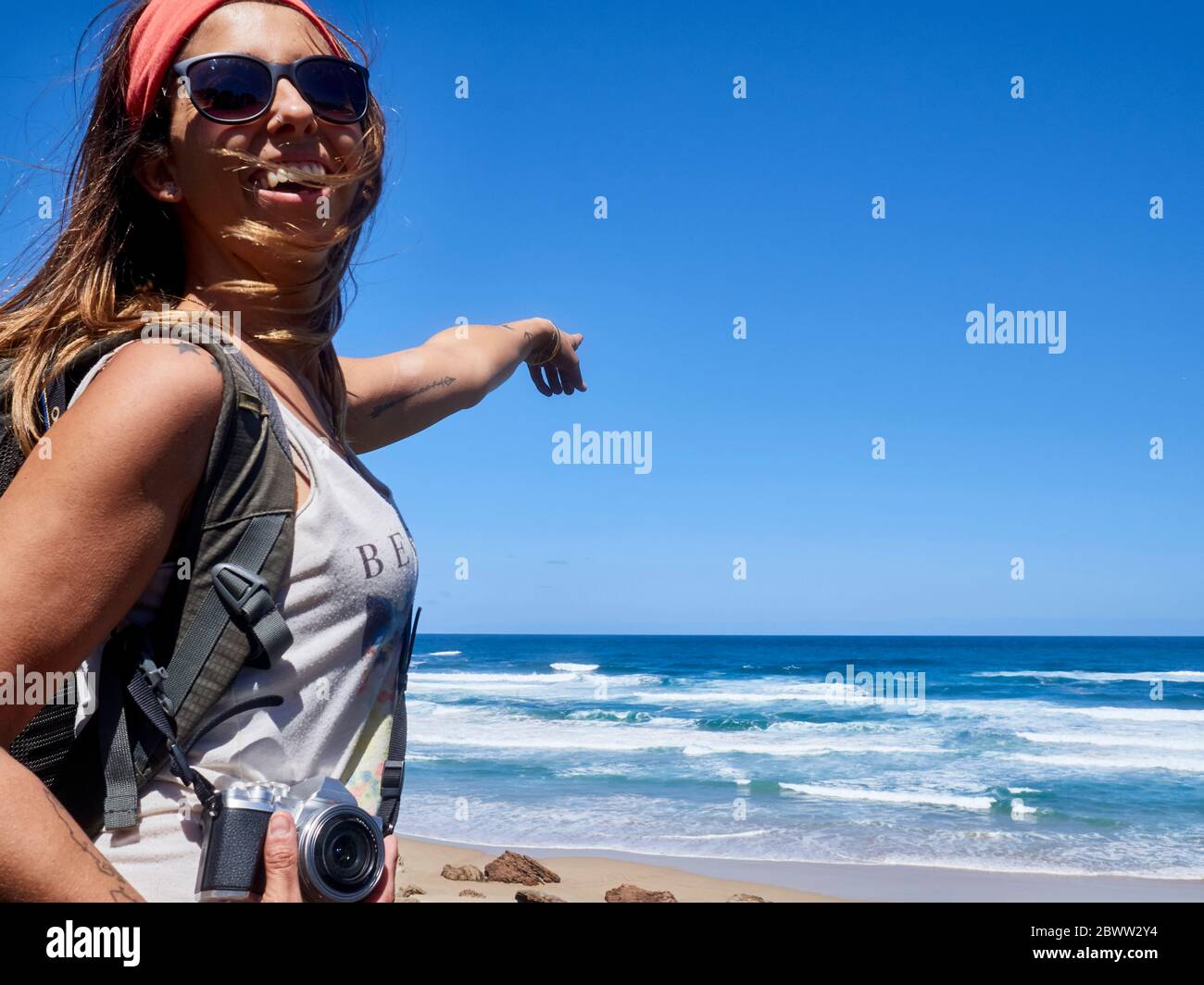 Une heureuse femme qui pointe du doigt vers l'océan, réserve naturelle de Robberg, Afrique du Sud Banque D'Images