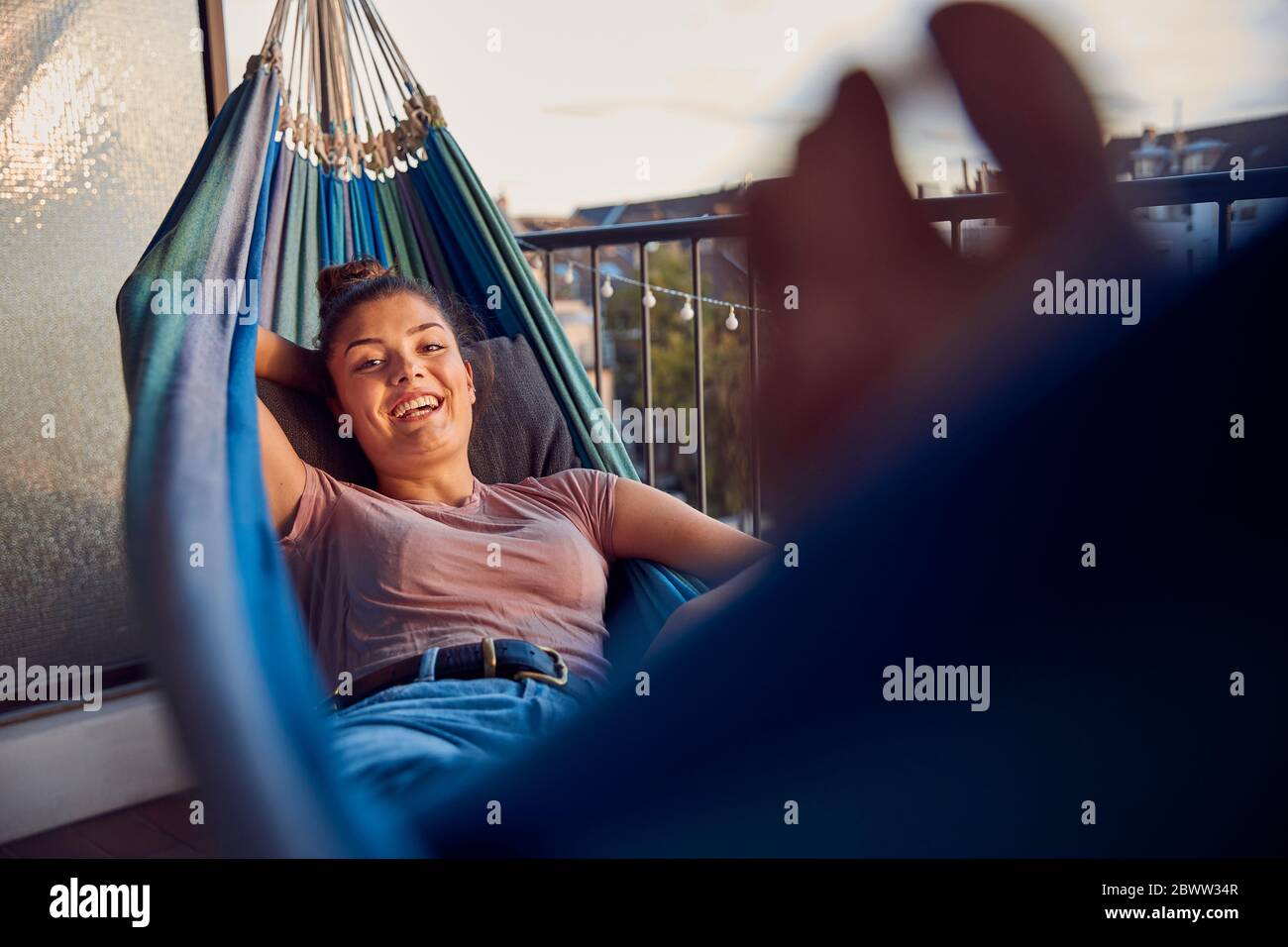 Portrait de la jeune femme heureuse se relaxant sur le hamac sur le balcon Banque D'Images