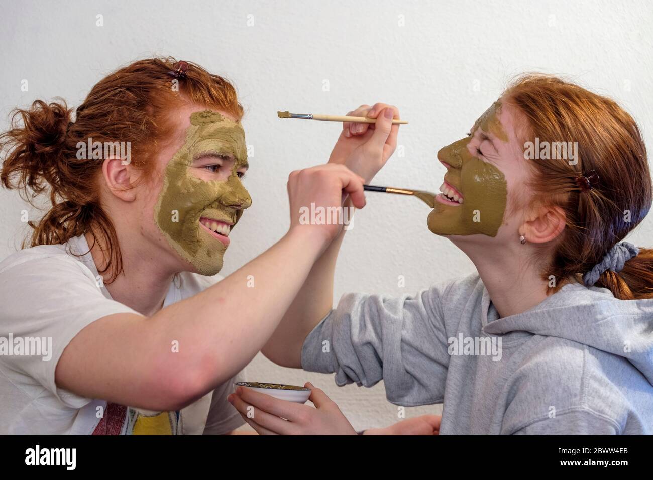 Frère et sœur appliquant le masque facial ayant le plaisir Banque D'Images