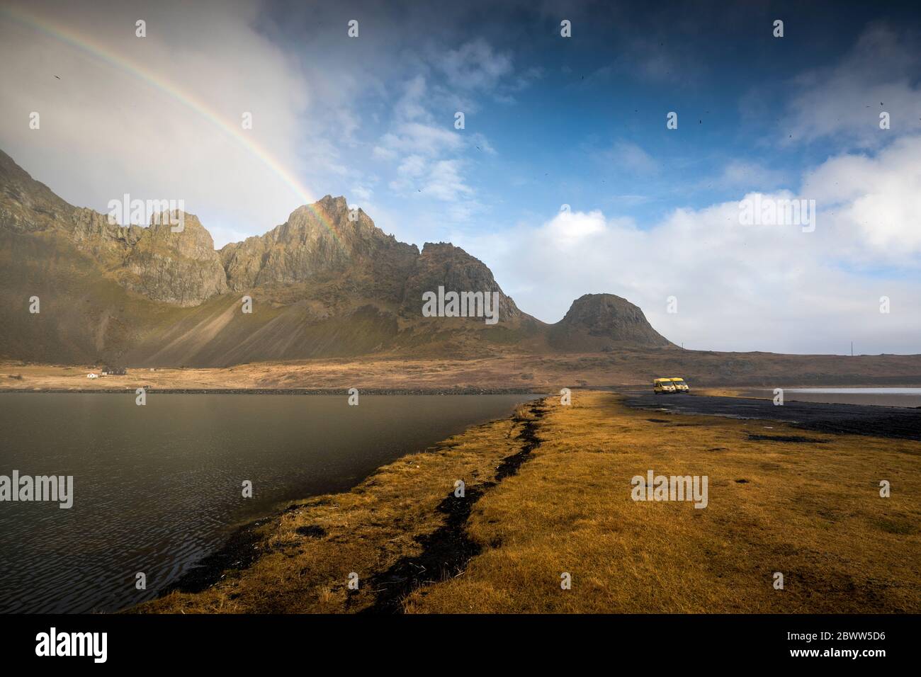 Vue panoramique sur la mer au milieu des montagnes contre l'arc-en-ciel dans le ciel à Hvalnes nature Reserve Beach, Islande Banque D'Images