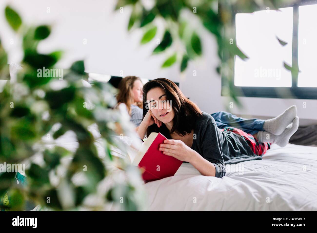 Portrait d'une femme allongé sur un lit lisant un livre Banque D'Images