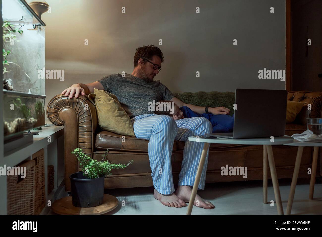 Homme assis par une fille malade dormant sur un canapé dans le salon à la maison pendant la quarantaine Banque D'Images