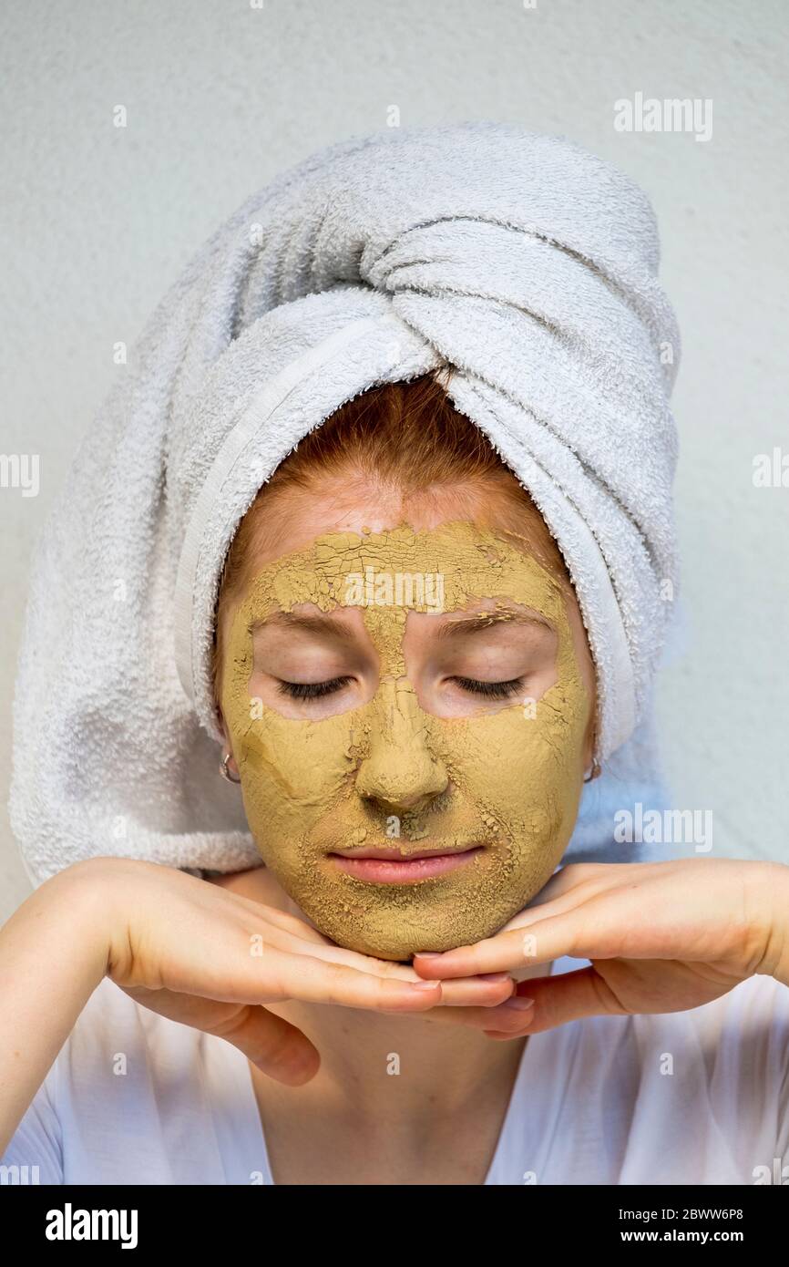 Portrait d'une adolescente avec masque facial enveloppé dans une serviette Banque D'Images