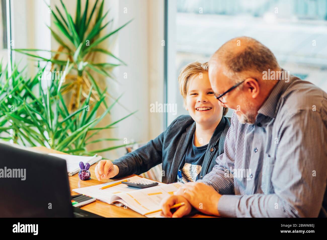 Père aidant son fils à faire ses devoirs à son bureau Banque D'Images