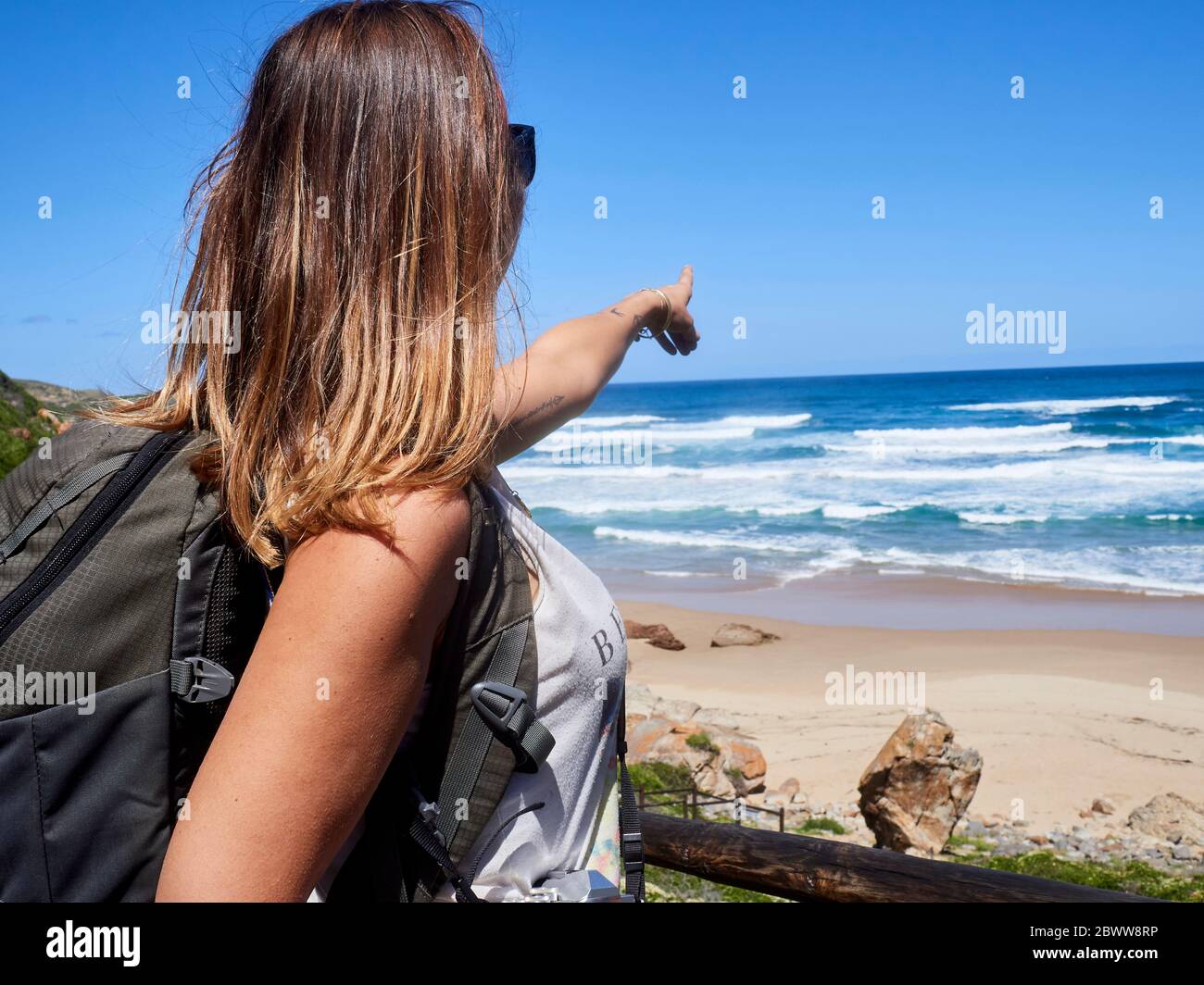 Sac à dos femme pointant avec son doigt vers l'océan, réserve naturelle de Robberg, Afrique du Sud Banque D'Images