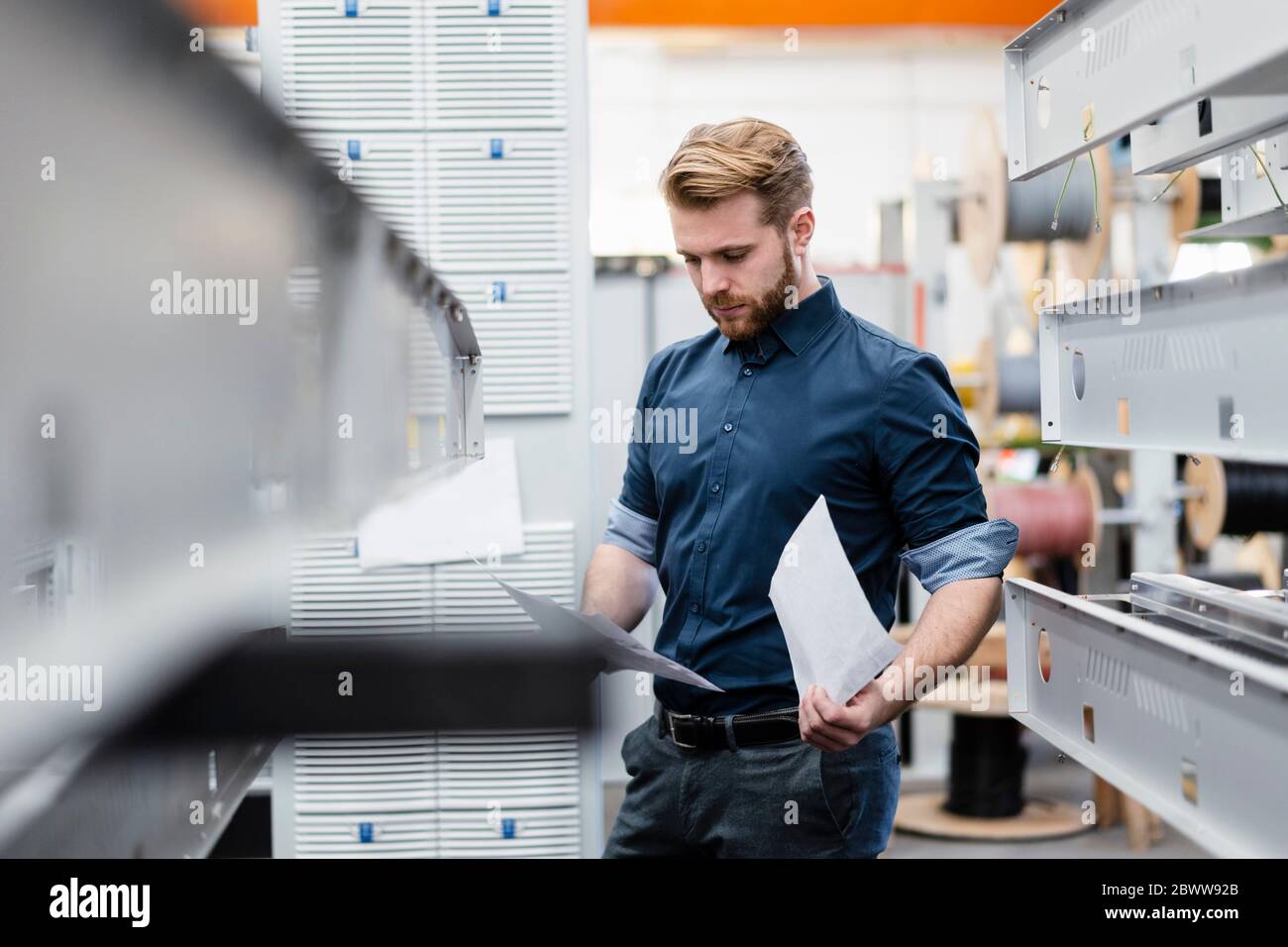Jeune homme regardant des papiers dans une usine Banque D'Images