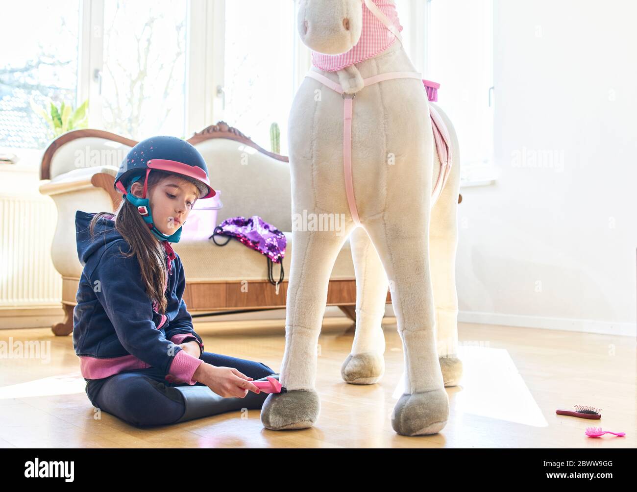 Fille toilettant son cheval jouet à la maison Banque D'Images