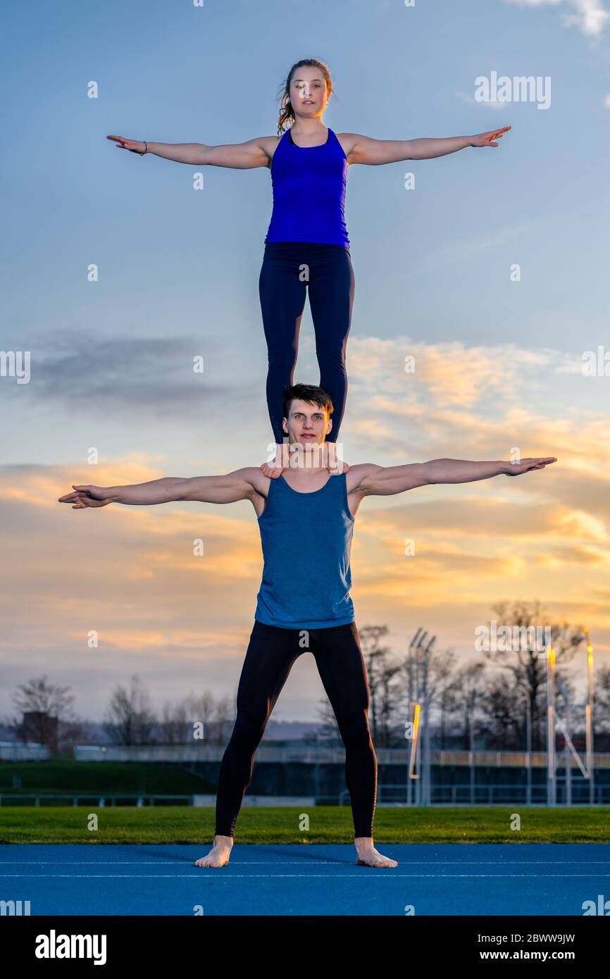 Jeune couple faisant des acrobaties au coucher du soleil Banque D'Images