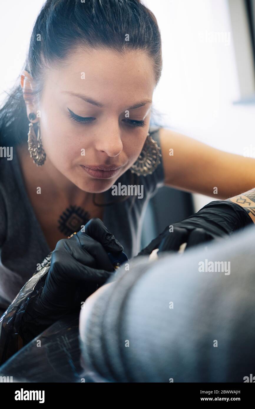 Tatoueur de femme tatouant sur le bras d'une femme Banque D'Images