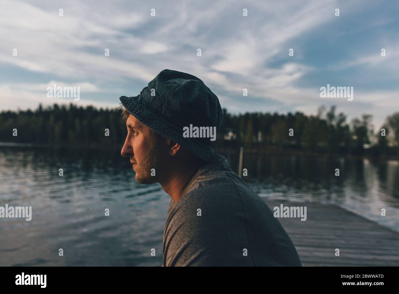 Jeune homme avec chapeau, regardant le lac Banque D'Images