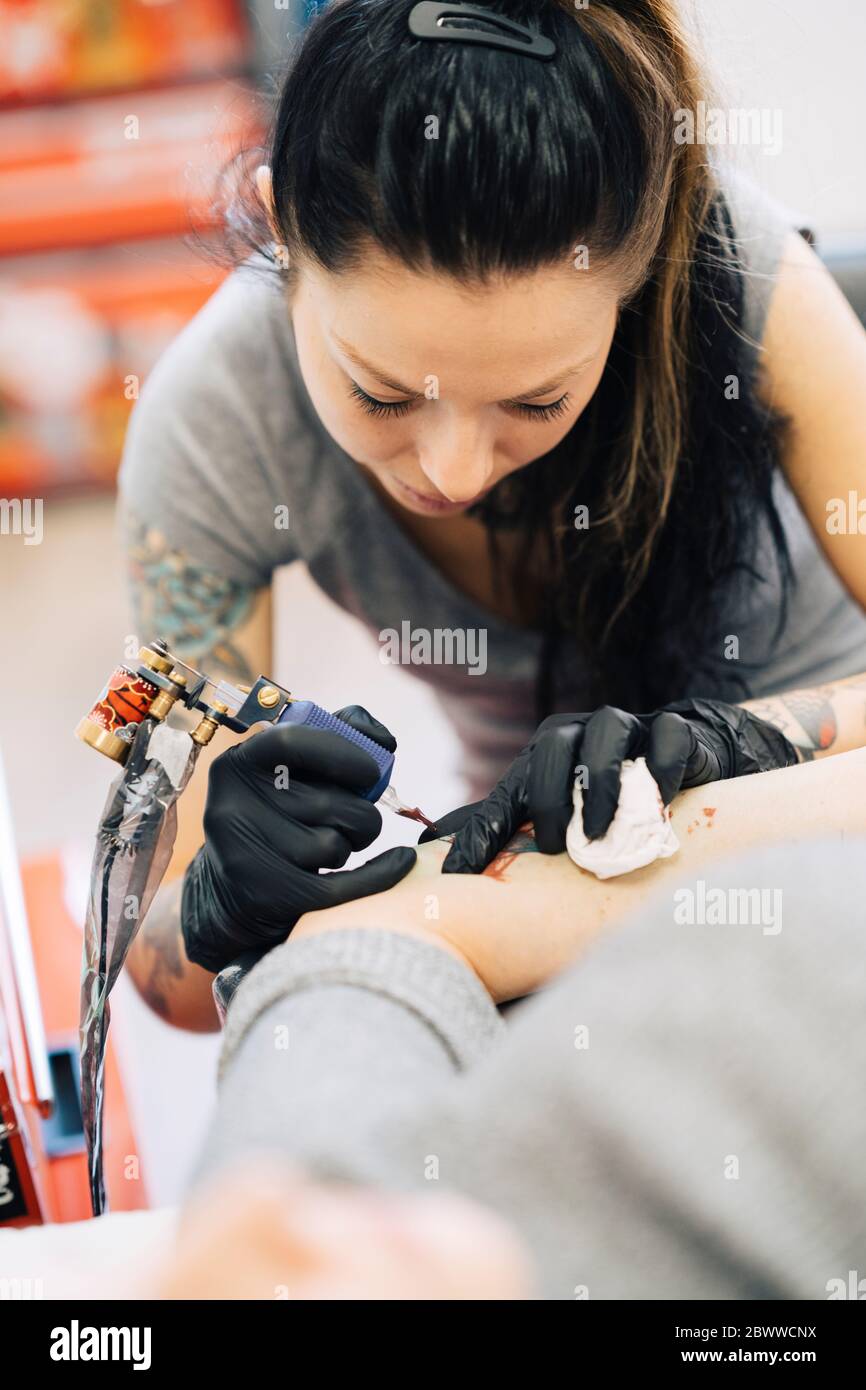 Tatoueur de femme tatouant sur le bras d'une femme Banque D'Images
