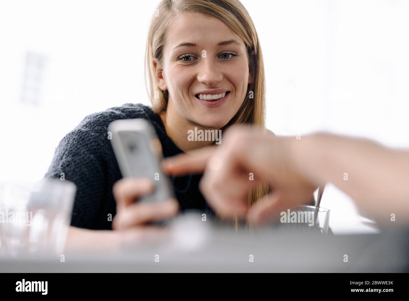 Portrait d'une jeune femme souriante et doigt pointant sur un smartphone Banque D'Images