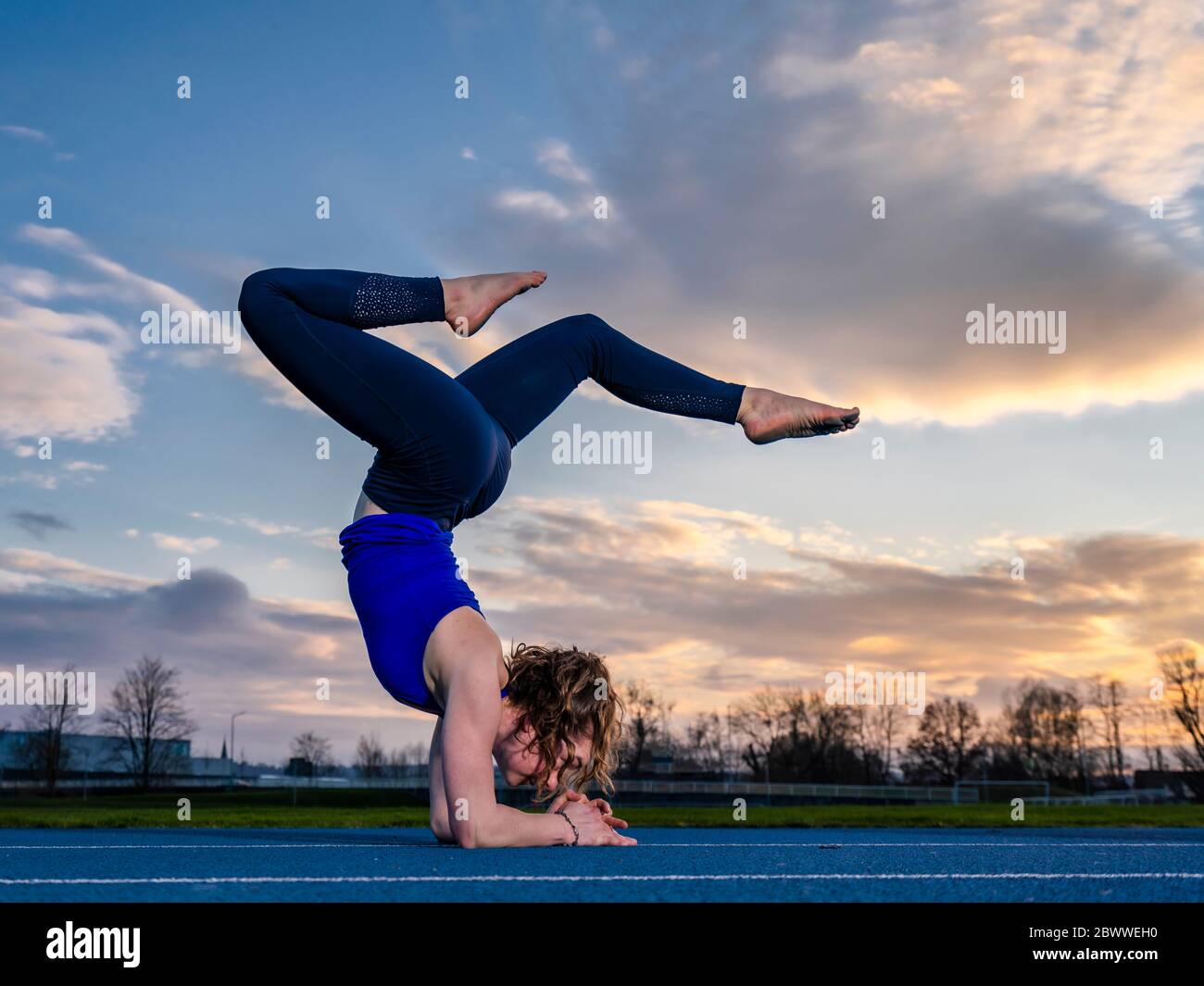 Jeune femme faisant des acrobaties au coucher du soleil Banque D'Images