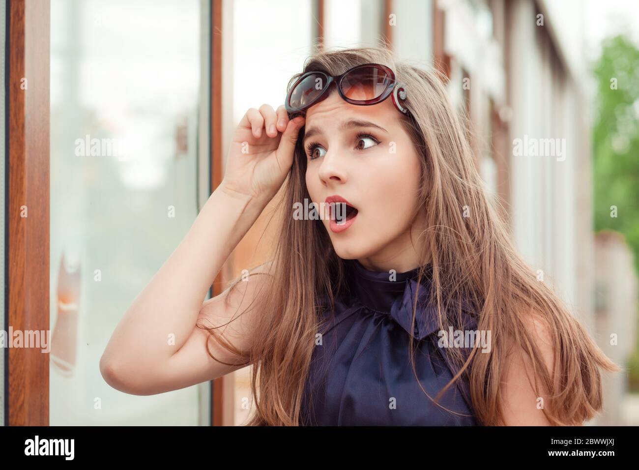 Super, super affaire. Surprise jeune femme tenant des lunettes de soleil  vers le haut regardant choqué par la fenêtre du magasin à la vente Photo  Stock - Alamy