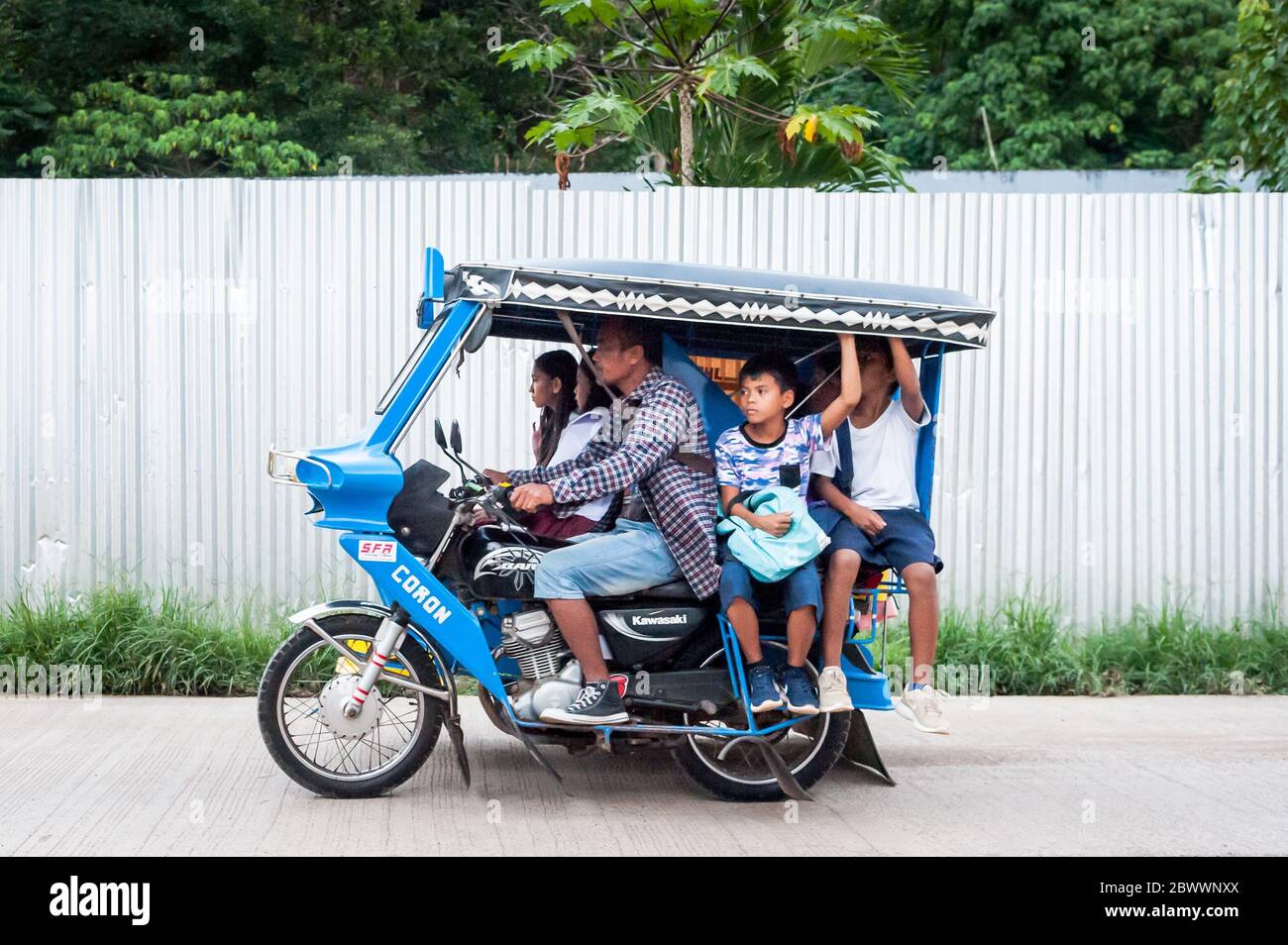 Le célèbre tricycle philippin ou tuk tuk (parfois appelé pousse-pousse) fait son chemin le long de la route principale très fréquentée allant dans Coron Town propre. Île Coron. Banque D'Images